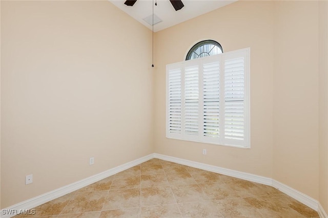 empty room with light tile patterned floors, baseboards, vaulted ceiling, and a ceiling fan