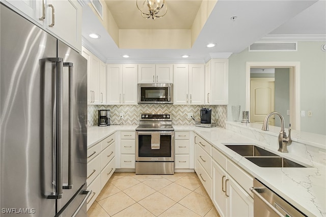 kitchen featuring a raised ceiling, decorative backsplash, appliances with stainless steel finishes, light stone counters, and sink