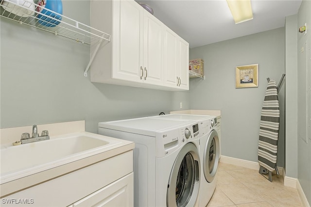 clothes washing area featuring washing machine and clothes dryer, light tile patterned flooring, cabinets, and sink