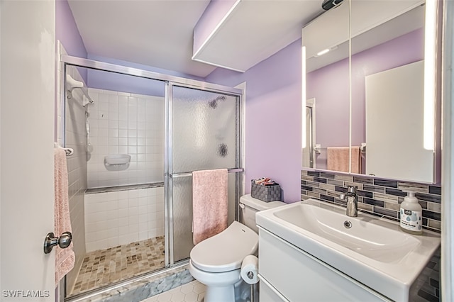 bathroom with backsplash, vanity, an enclosed shower, and toilet