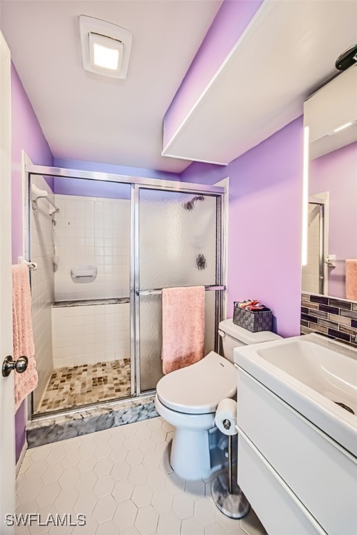 bathroom featuring tile patterned flooring, vanity, toilet, and an enclosed shower