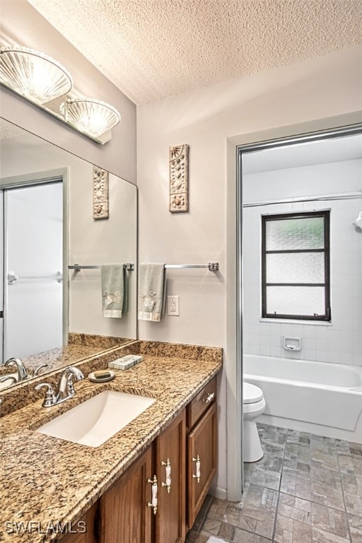 full bathroom with vanity, toilet, a textured ceiling, and tiled shower / bath combo