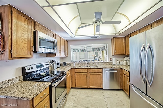 kitchen featuring light stone countertops, appliances with stainless steel finishes, ceiling fan, sink, and light tile patterned flooring