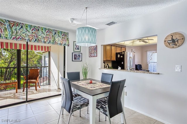 tiled dining room with a textured ceiling and ceiling fan