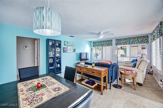 tiled dining room with ceiling fan and a textured ceiling