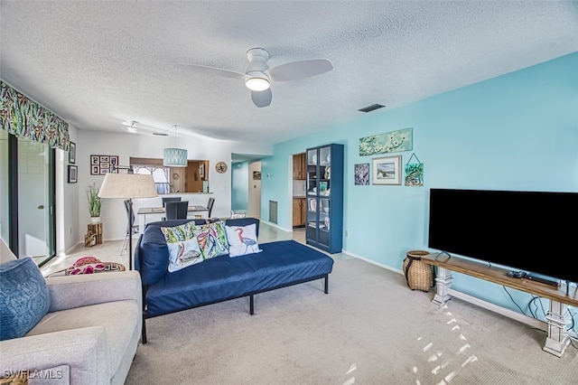 living room with ceiling fan, light carpet, and a textured ceiling