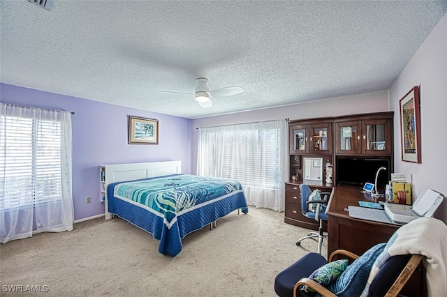 carpeted bedroom with multiple windows, a textured ceiling, and ceiling fan