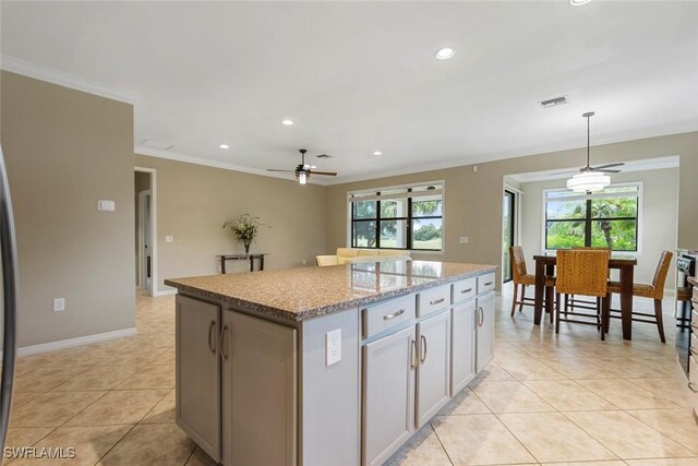 kitchen featuring ceiling fan, crown molding, a center island, hanging light fixtures, and light tile patterned flooring