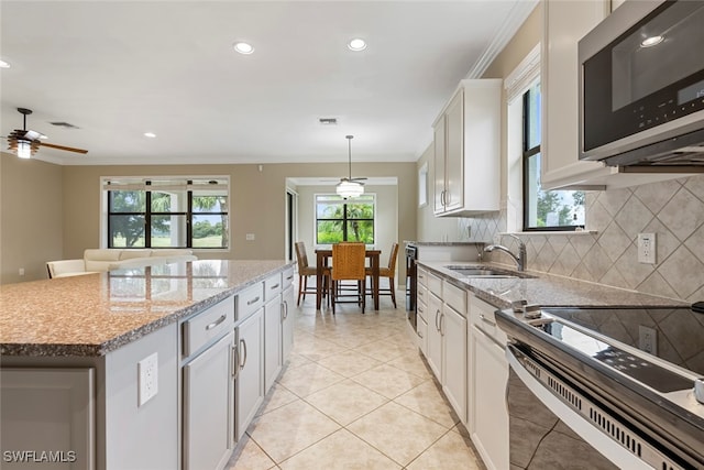 kitchen with a center island, sink, ceiling fan, appliances with stainless steel finishes, and white cabinetry