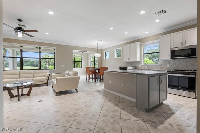 kitchen featuring white cabinets, ceiling fan, tasteful backsplash, a kitchen island, and stainless steel appliances