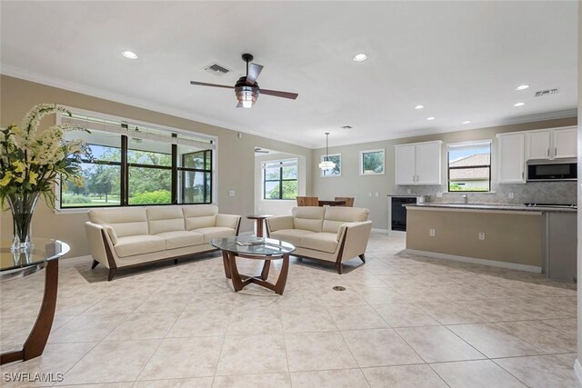 living room with crown molding, ceiling fan, and light tile patterned flooring