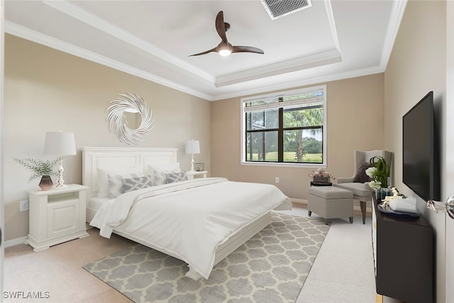 carpeted bedroom with ceiling fan, a raised ceiling, and crown molding