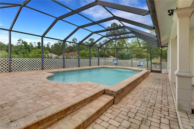 view of swimming pool featuring glass enclosure and a patio area