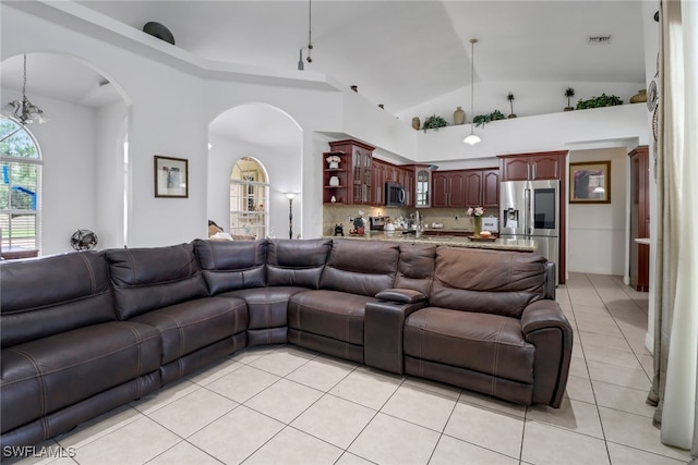 tiled living room featuring high vaulted ceiling and an inviting chandelier