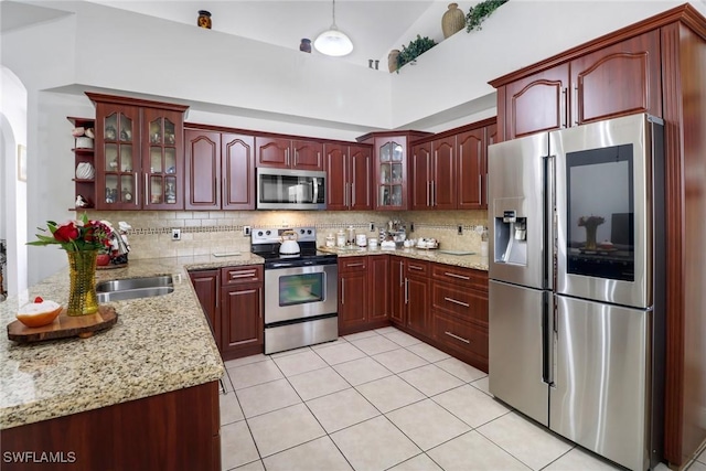 3711 4th Ave SE, Naples, FL 34117 - kitchen featuring stainless steel appliances, backsplash, light stone countertops, light tile patterned floors, and high vaulted ceiling