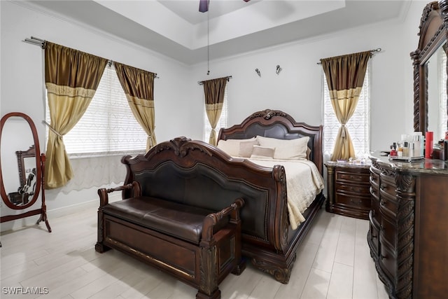 bedroom featuring ceiling fan, light wood-type flooring, and a tray ceiling