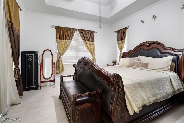 bedroom featuring light hardwood / wood-style floors, ornamental molding, and a raised ceiling