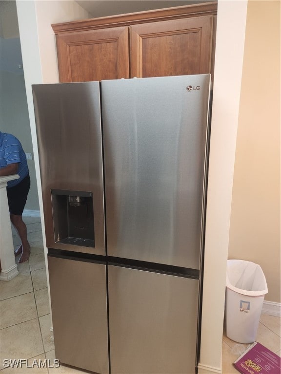 room details featuring stainless steel refrigerator with ice dispenser and light tile patterned floors