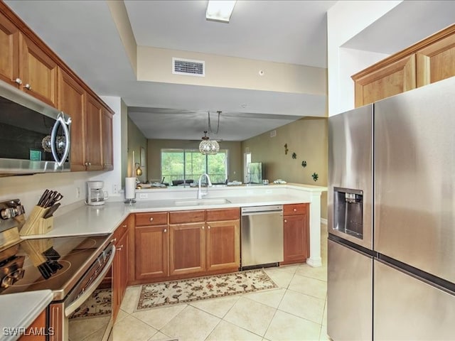 kitchen featuring stainless steel appliances, light tile patterned flooring, sink, kitchen peninsula, and pendant lighting