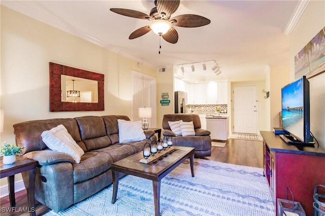 living room with dark hardwood / wood-style flooring, ceiling fan, and crown molding