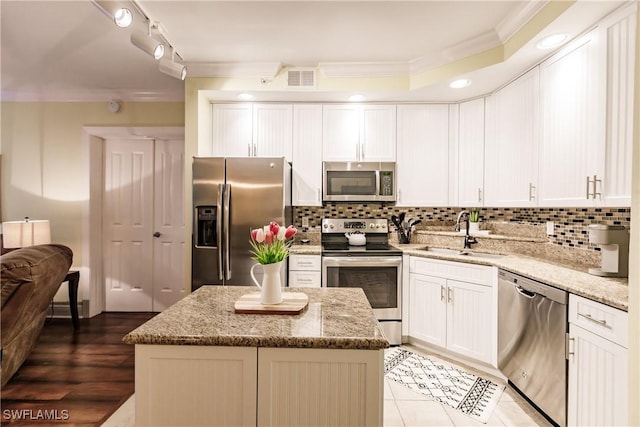 kitchen with crown molding, a kitchen island, sink, and stainless steel appliances