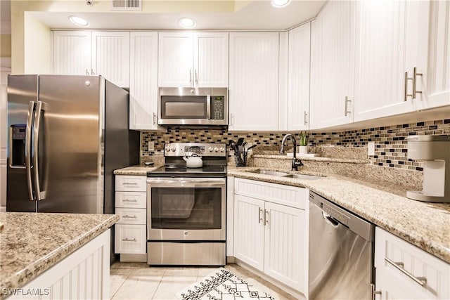 kitchen featuring decorative backsplash, white cabinetry, and appliances with stainless steel finishes