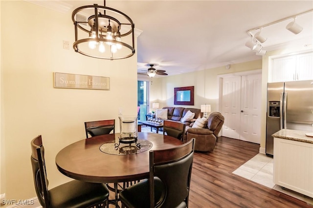 dining area with ceiling fan with notable chandelier and light hardwood / wood-style floors