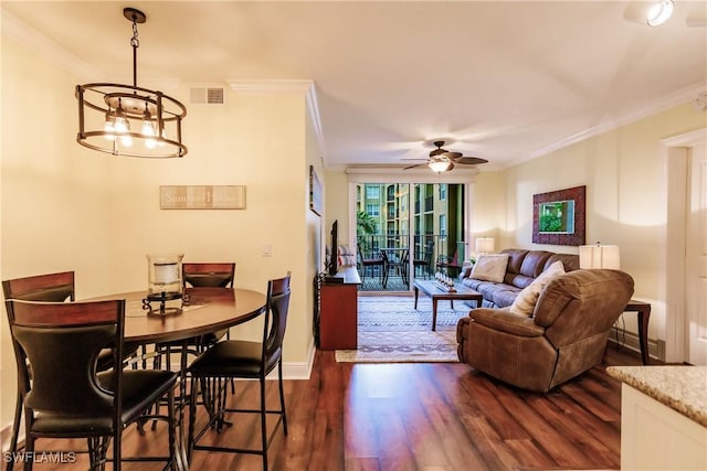 dining area with ornamental molding, ceiling fan with notable chandelier, and dark wood-type flooring