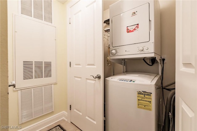 laundry room with water heater and stacked washer / drying machine