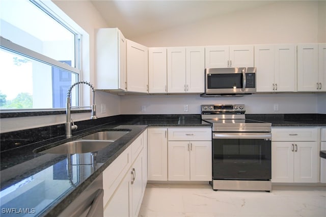 kitchen featuring stainless steel appliances, light tile patterned floors, vaulted ceiling, sink, and white cabinetry