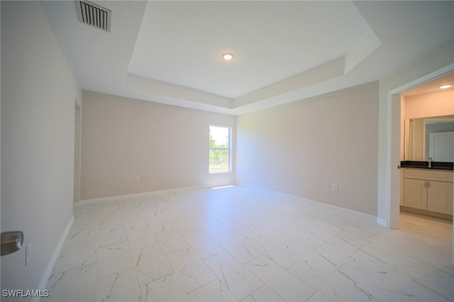 empty room with a raised ceiling and light tile patterned floors