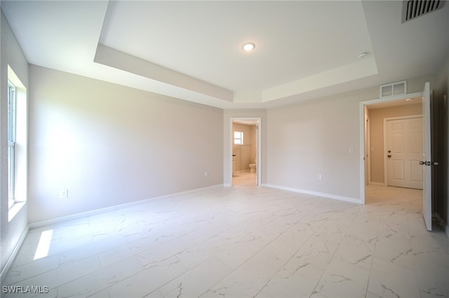 unfurnished room with a raised ceiling and light tile patterned floors