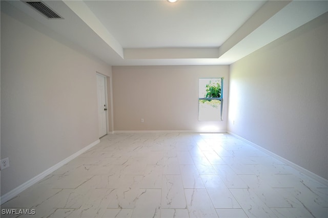 tiled spare room featuring a tray ceiling