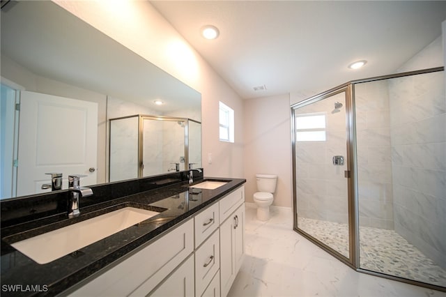 bathroom with dual bowl vanity, a shower with shower door, and toilet