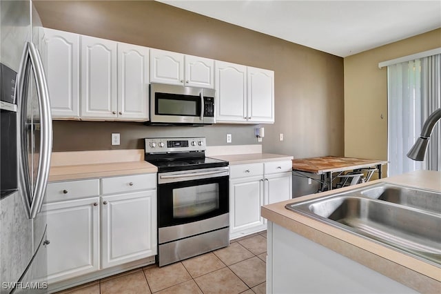 kitchen featuring sink, stainless steel appliances, white cabinetry, and light tile patterned floors