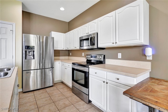 kitchen featuring light tile patterned floors, white cabinets, and stainless steel appliances