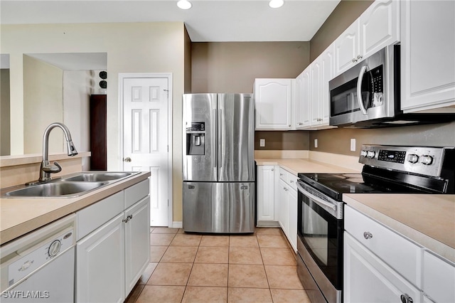 kitchen featuring appliances with stainless steel finishes, sink, white cabinetry, and light tile patterned floors