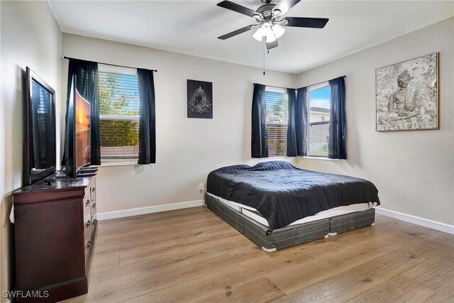 bedroom with light hardwood / wood-style flooring, ceiling fan, and multiple windows