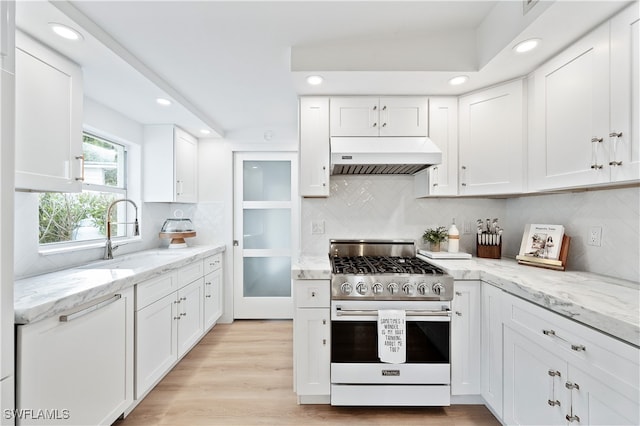 kitchen with extractor fan, sink, white cabinets, light hardwood / wood-style floors, and stainless steel range with gas stovetop