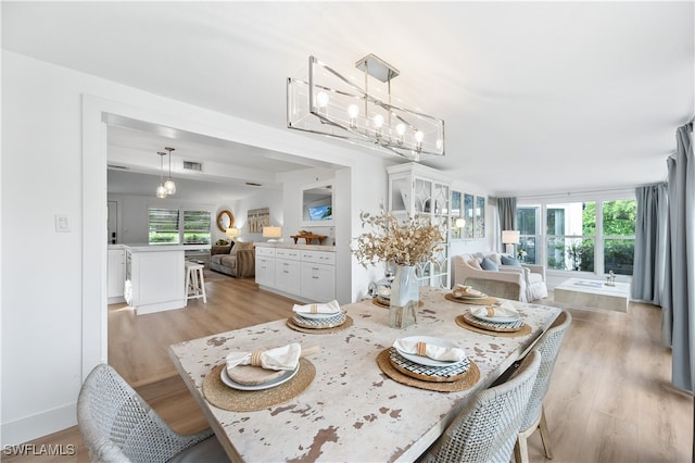 dining area featuring a healthy amount of sunlight, light hardwood / wood-style flooring, and a chandelier