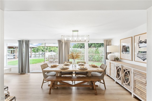 dining space with light hardwood / wood-style flooring, a notable chandelier, and a wealth of natural light