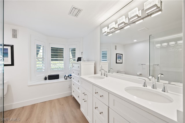 bathroom with hardwood / wood-style flooring, vanity, toilet, and a shower with shower door