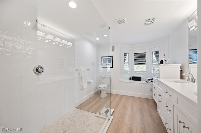 bathroom with vanity, hardwood / wood-style flooring, and tiled shower