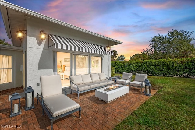 patio terrace at dusk with a lawn and an outdoor living space with a fire pit