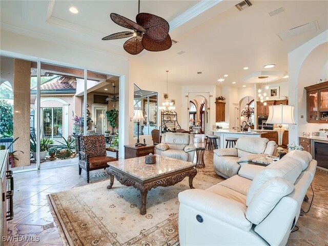 living room featuring sink, ceiling fan with notable chandelier, ornamental molding, and beverage cooler