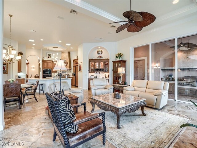 living room with crown molding, a raised ceiling, and ceiling fan with notable chandelier