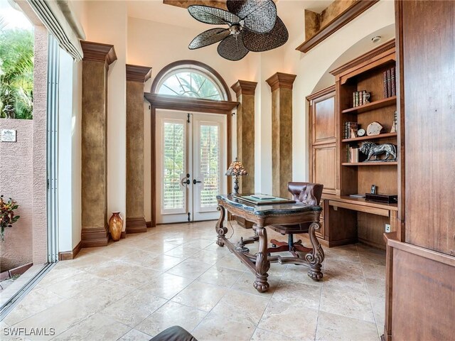 home office featuring a towering ceiling, built in desk, ceiling fan, and french doors