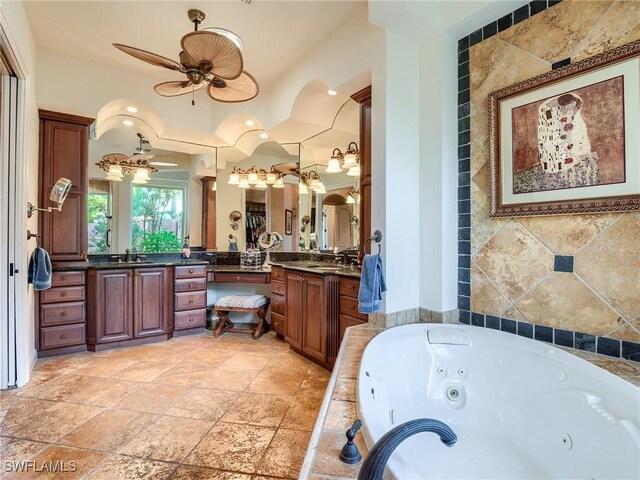 bathroom with ceiling fan, vanity, and tiled tub