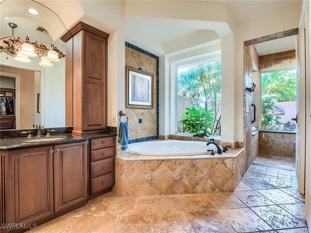 bathroom with vanity and tiled tub