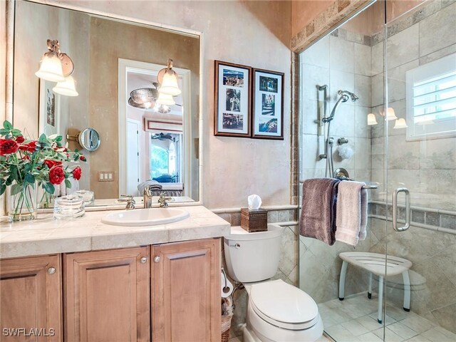 bathroom with vanity, a shower with shower door, tile walls, and toilet